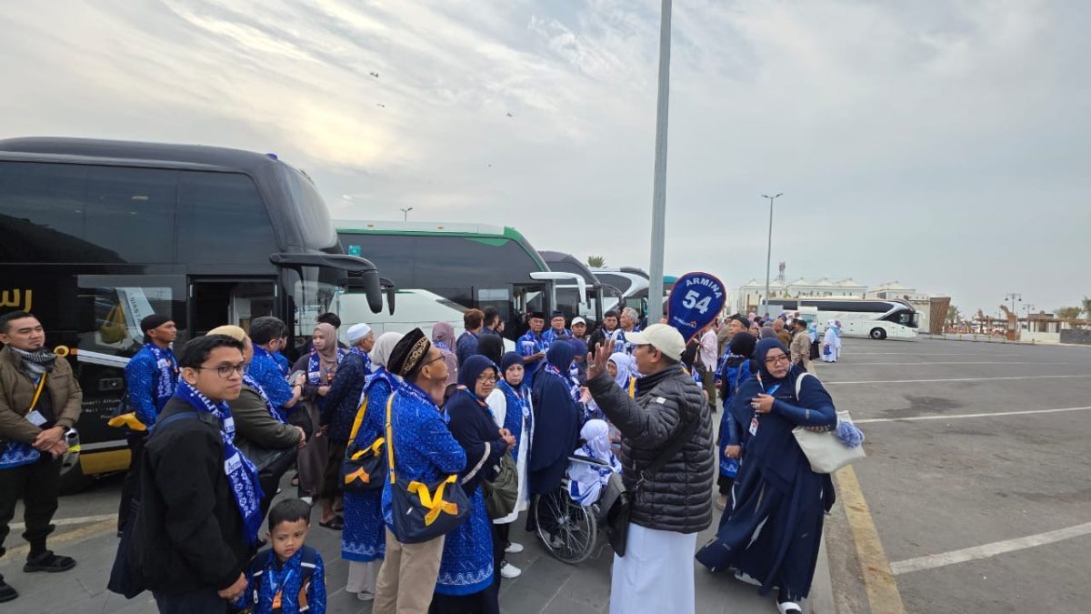 Rombongan jamaah umroh berkumpul di area parkir bus